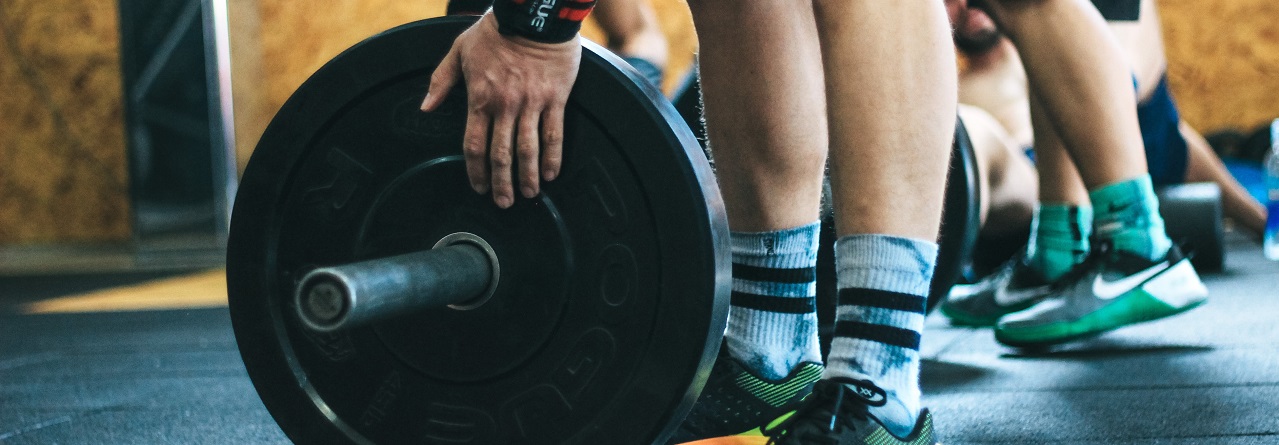 People in gym environment putting weights onto bar
