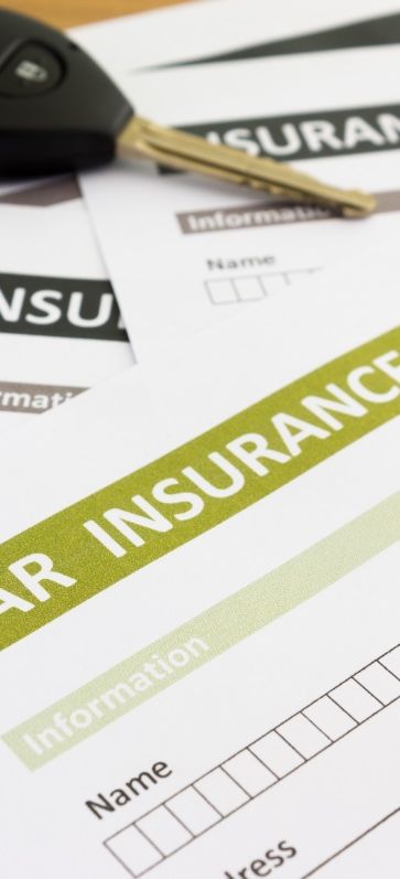 A car key places on top a few insurance form
