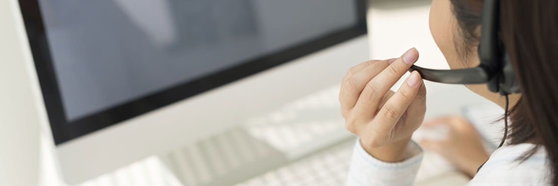 The back of a women wearing a headset sitting in front of a screen