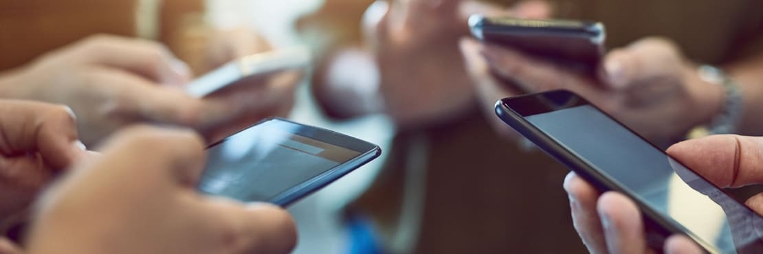 4 people gathering together using their smartphone to vote